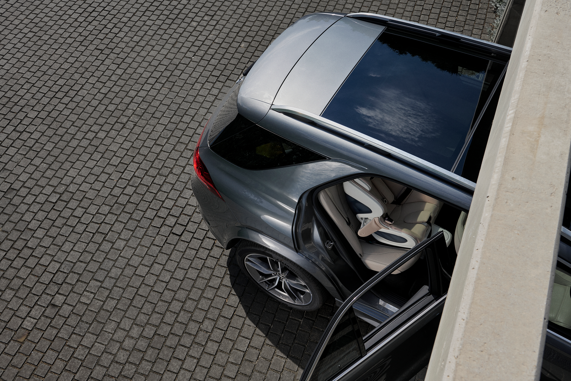 picture from above outside of a luxury car with the back passenger door open to show the babyark convertible car seat with side impact protection open on a hot day