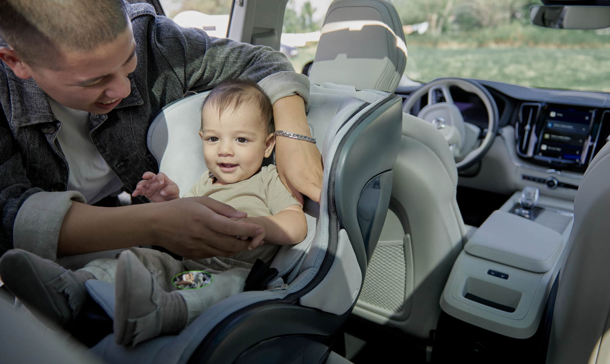 man buckles the 5 point harness on a baby into a lush babyark convertible car seat, rear facing