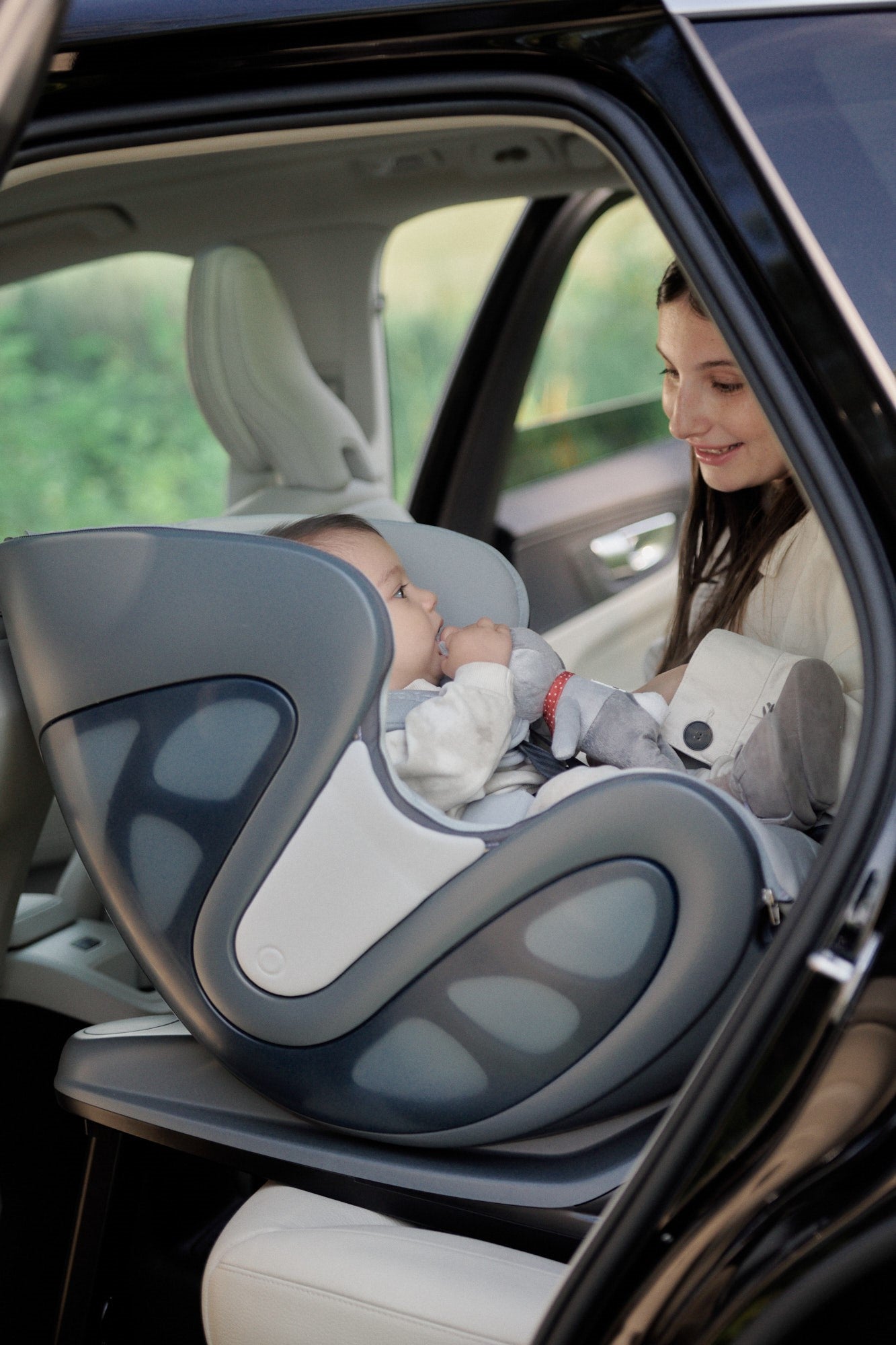 rear-facing babyark car seat, baby looks at mother who is standing in the doorway of the car